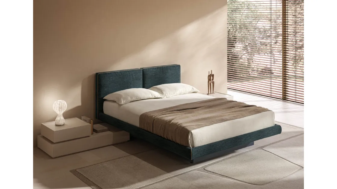 Blue upholstered bed with narrow storage box by Tagliabue Mobili.